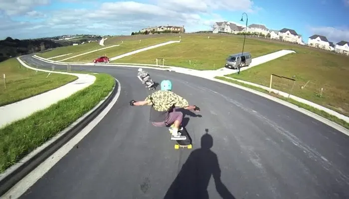 A rider in a helmet leaning into a bend on a smooth downhill road