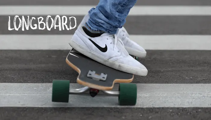 Sneakers on a longboard deck set across white road markings
